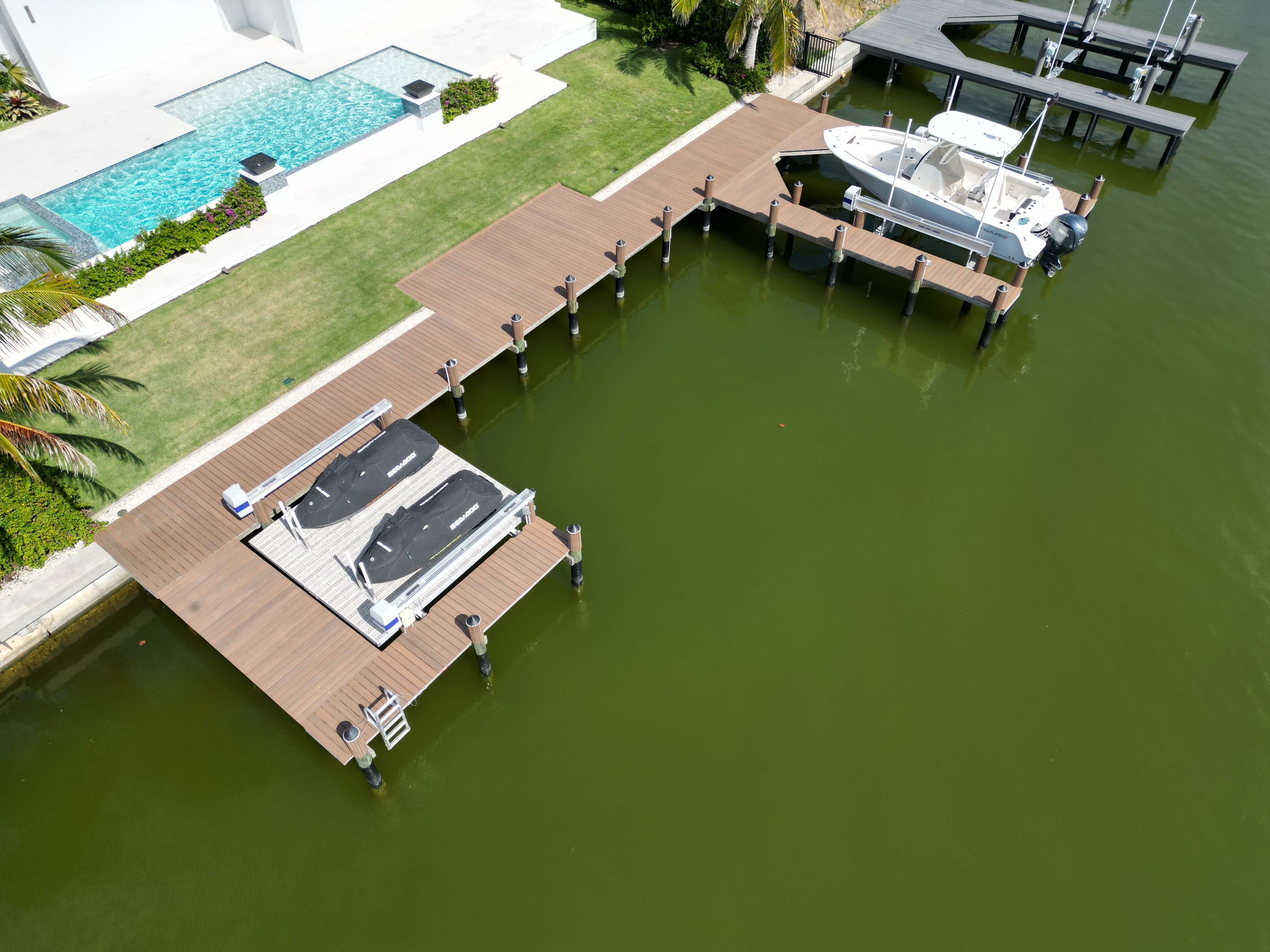 Aerial view of custom boat dock with decking, boat lift, and waterfront property.
