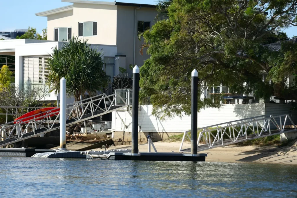 A modern waterfront home featuring a private boat jetty and gangway, highlighting dock maintenance needs.