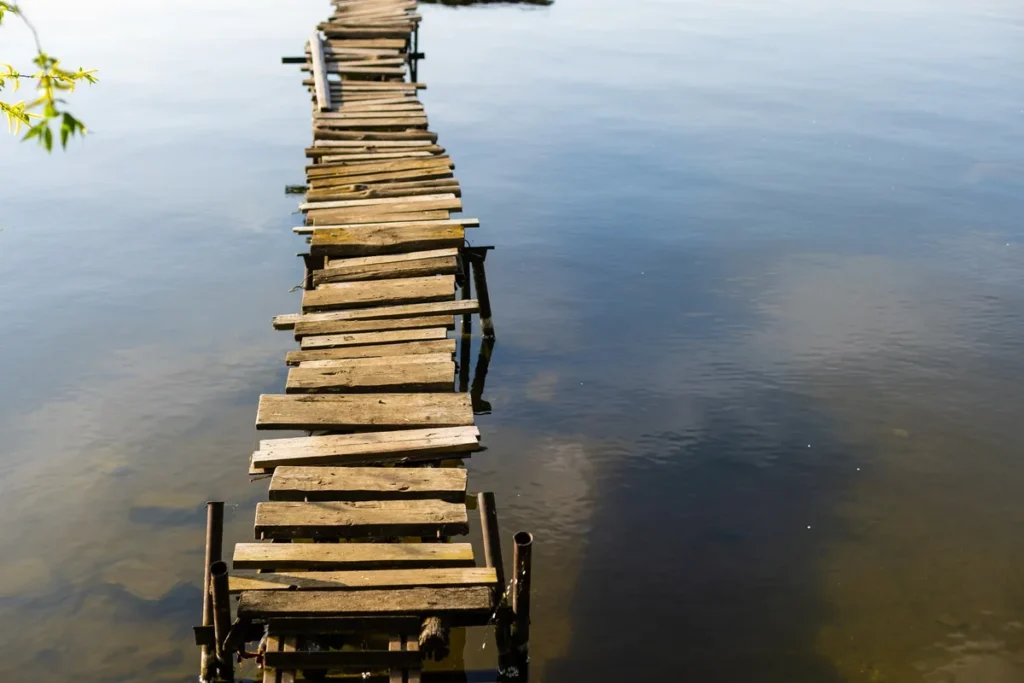 A river shore with a small bridge and a fisherman, highlighting the importance of secure dock safety.