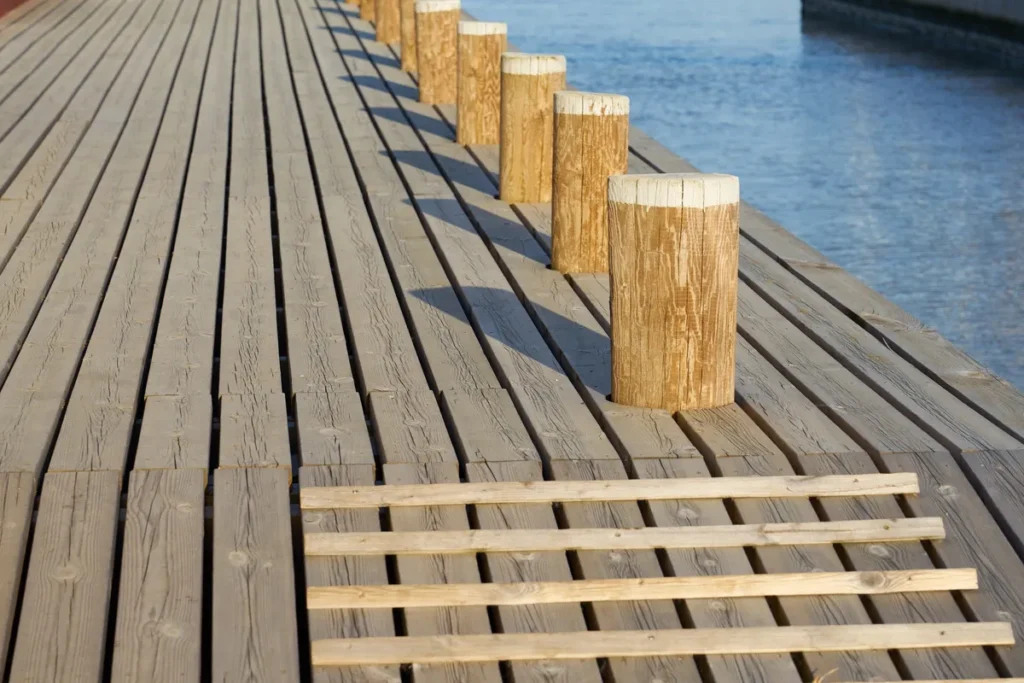Wooden mooring bollards casting shadows on a mole, highlighting potential risks in DIY dock installation.